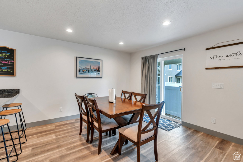 Dining room with light wood finished floors, recessed lighting, baseboards, and a textured ceiling