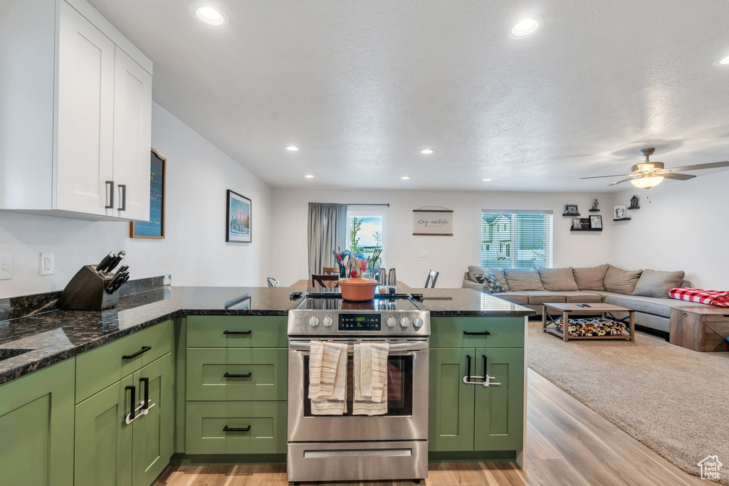 Kitchen with stainless steel electric stove, green cabinetry, white cabinets, light wood-type flooring, and recessed lighting