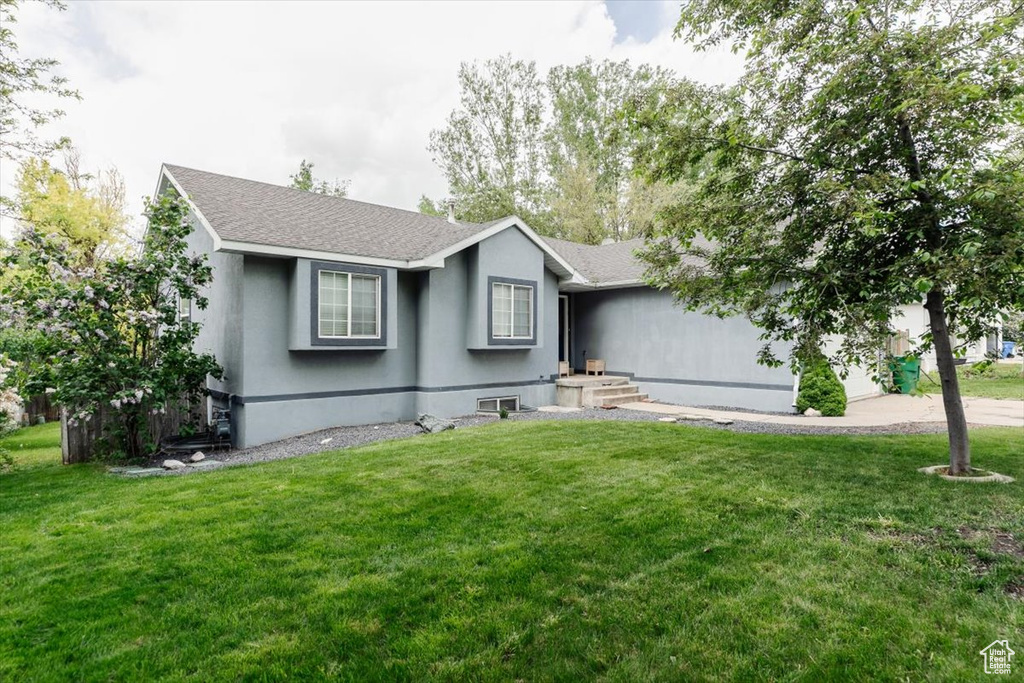 Ranch-style house featuring a front yard, a shingled roof, and stucco siding