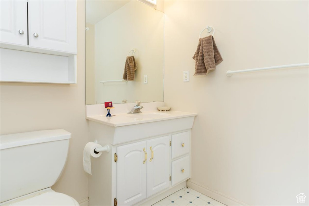 Bathroom with toilet, vanity, and baseboards