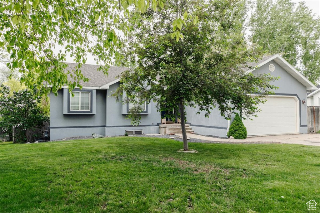 View of front facade with a garage, a front lawn, concrete driveway, stucco siding, and roof with shingles