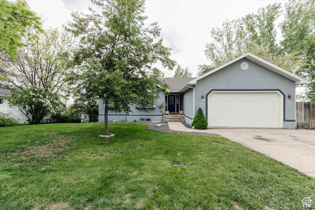 Ranch-style house with an attached garage, driveway, a front yard, stucco siding, and entry steps