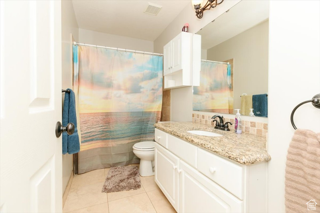 Bathroom with tile patterned floors, vanity, toilet, and curtained shower