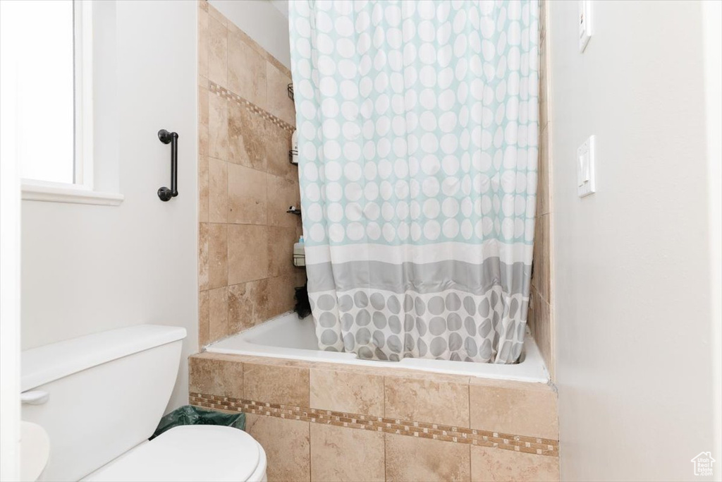 Bathroom with toilet and tiled shower / bath combo