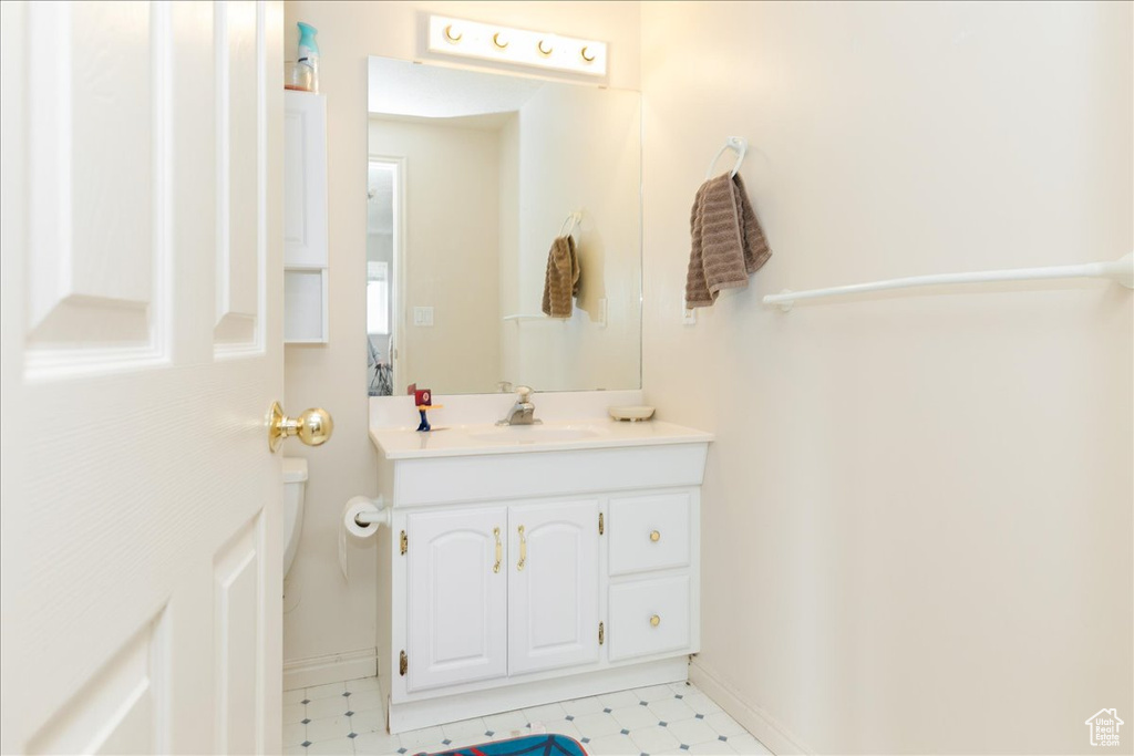 Bathroom featuring vanity, tile patterned floors, baseboards, and toilet