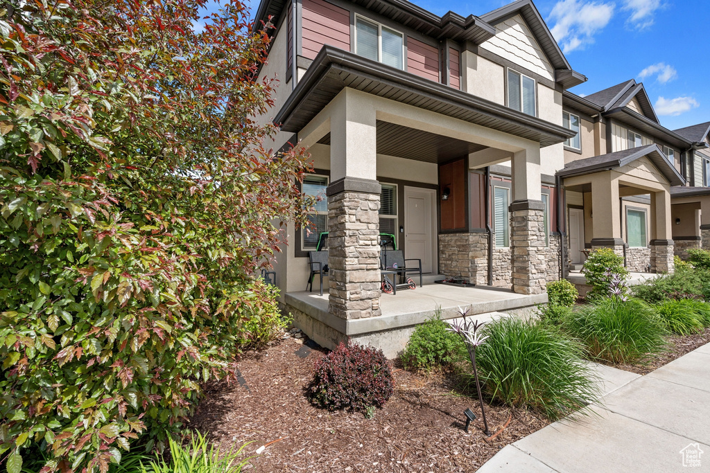 View of front of house with a porch, stucco siding, and stone siding