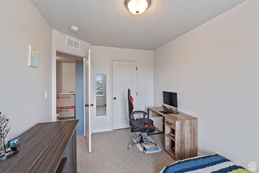 Bedroom featuring a textured ceiling, an office area, and carpet