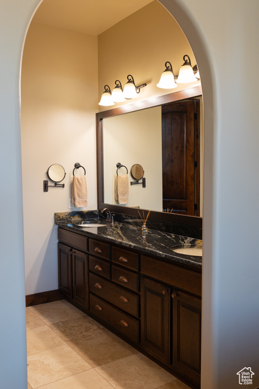 Bathroom with double vanity, baseboards, and tile patterned floors
