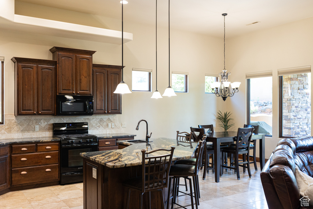 Kitchen with black appliances, dark stone countertops, a sink, backsplash, and a towering ceiling