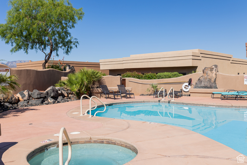 Community pool featuring a patio area, a community hot tub, and fence