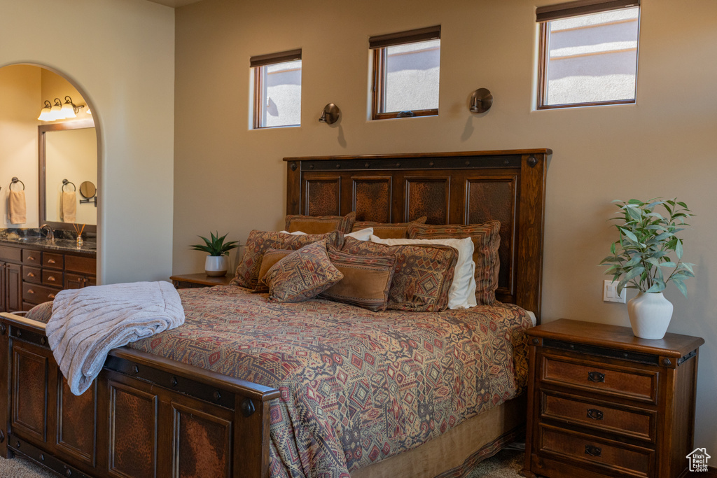 Bedroom featuring ensuite bathroom and arched walkways