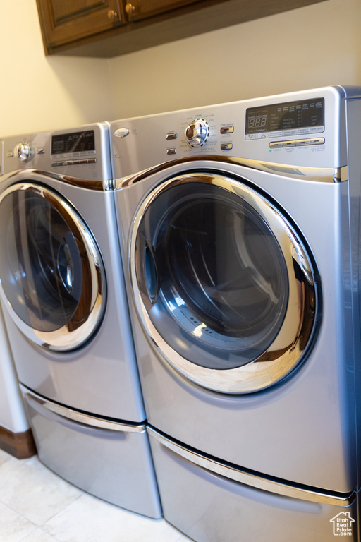 Clothes washing area featuring cabinet space, washing machine and dryer, and tile patterned flooring
