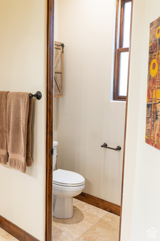 Bathroom featuring toilet, baseboards, and tile patterned floors