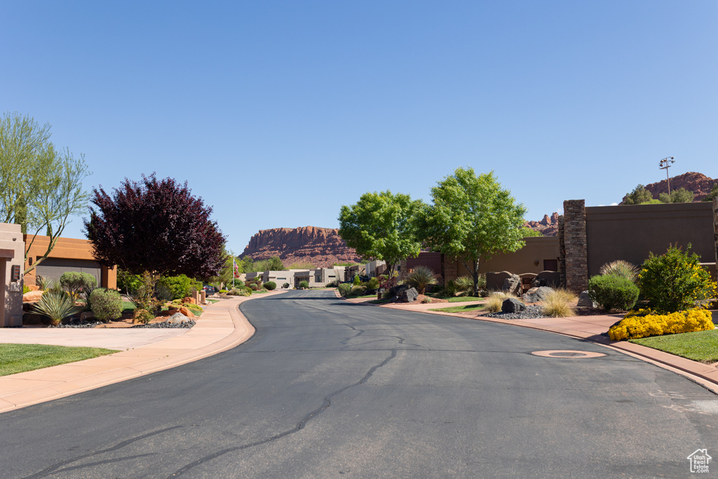 View of asphalt road with a mountain view, sidewalks, and curbs