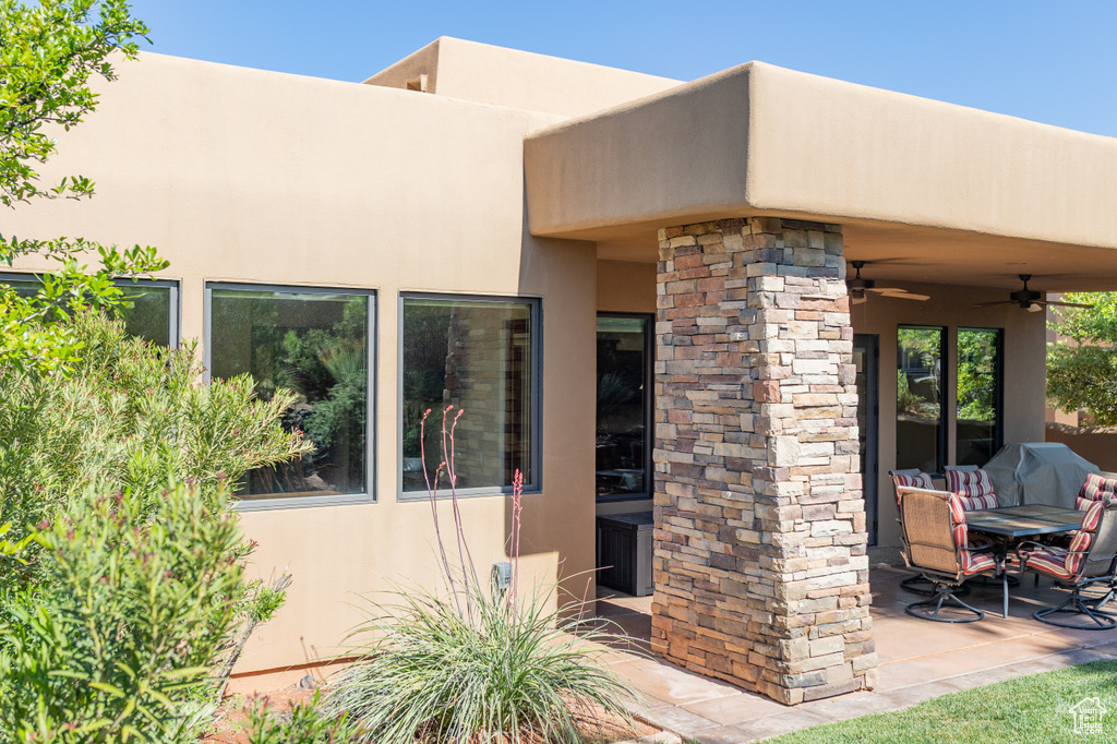 View of exterior entry with stucco siding, ceiling fan, and a patio area