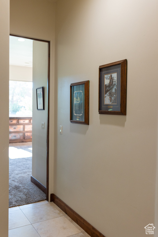 Corridor featuring light colored carpet, light tile patterned flooring, and baseboards