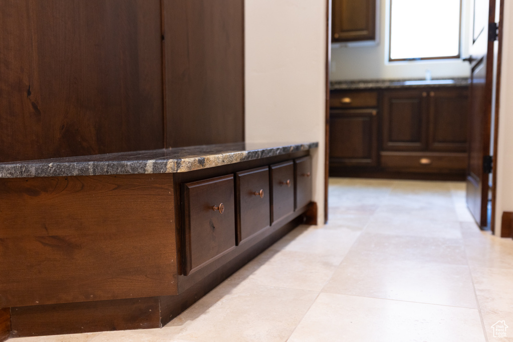 Kitchen with light flooring, dark brown cabinets, dark countertops, and a sink