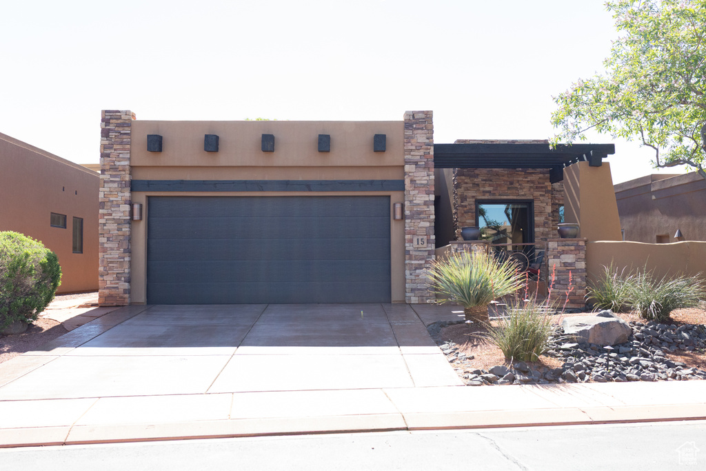 Pueblo-style home with concrete driveway, an attached garage, and stucco siding