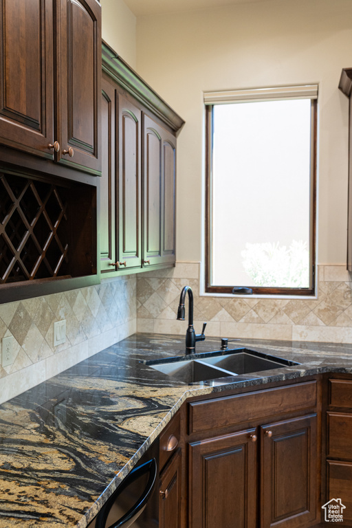 Kitchen with a sink, tasteful backsplash, dark brown cabinetry, and dark stone counters