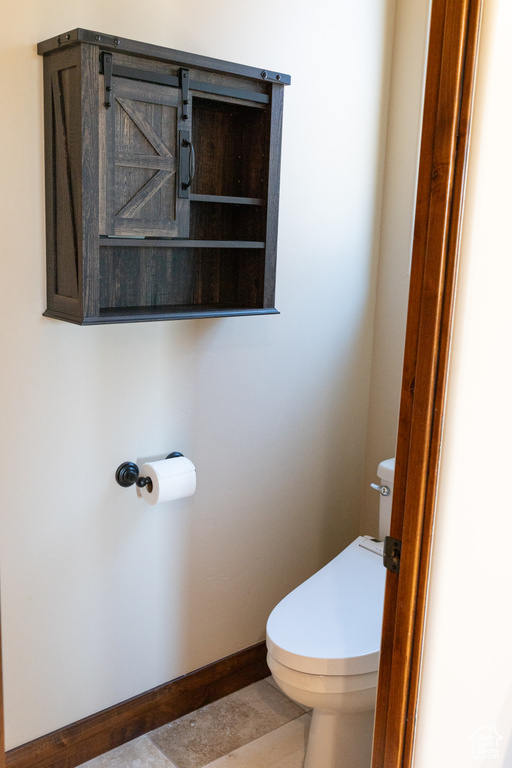 Bathroom with toilet, baseboards, and tile patterned flooring