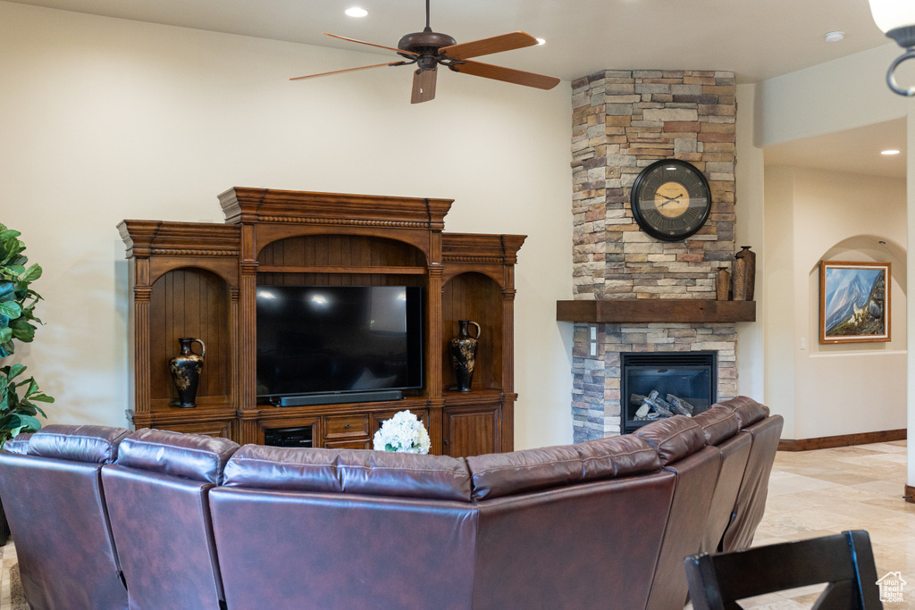 Living area with ceiling fan, a stone fireplace, baseboards, and recessed lighting