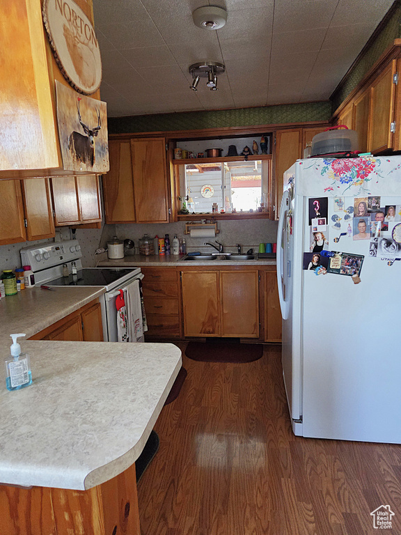 Kitchen with white appliances, a sink, and brown cabinets