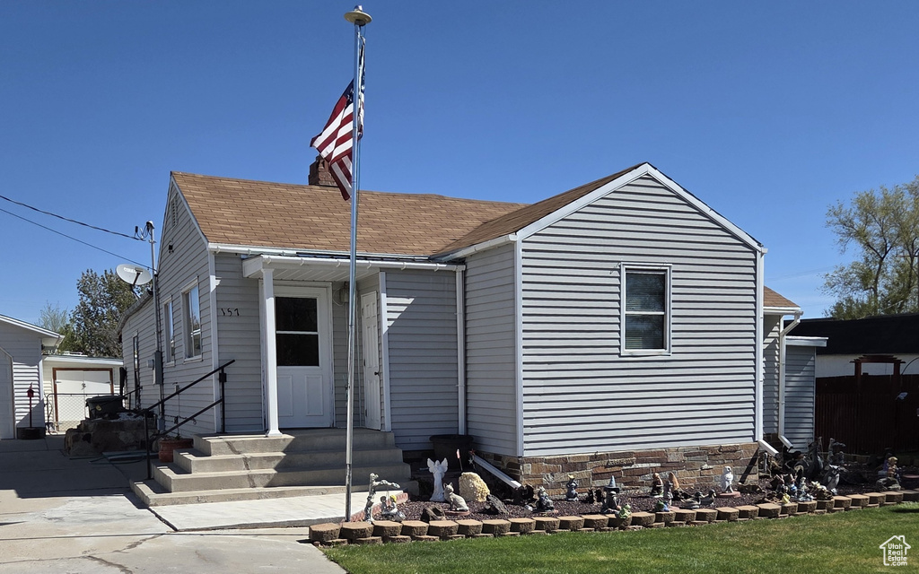 View of front of property featuring entry steps, a chimney, and roof with shingles