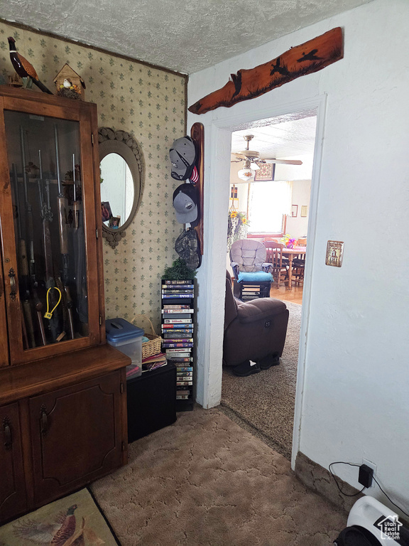 Hallway with carpet floors, wallpapered walls, and a textured ceiling