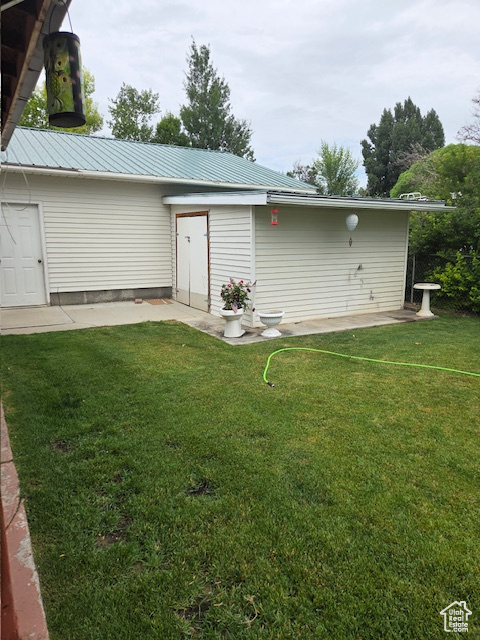 Back of house with a lawn, a metal roof, and a patio