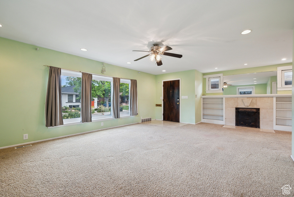 Unfurnished living room with ceiling fan, recessed lighting, carpet flooring, a tile fireplace, and baseboards