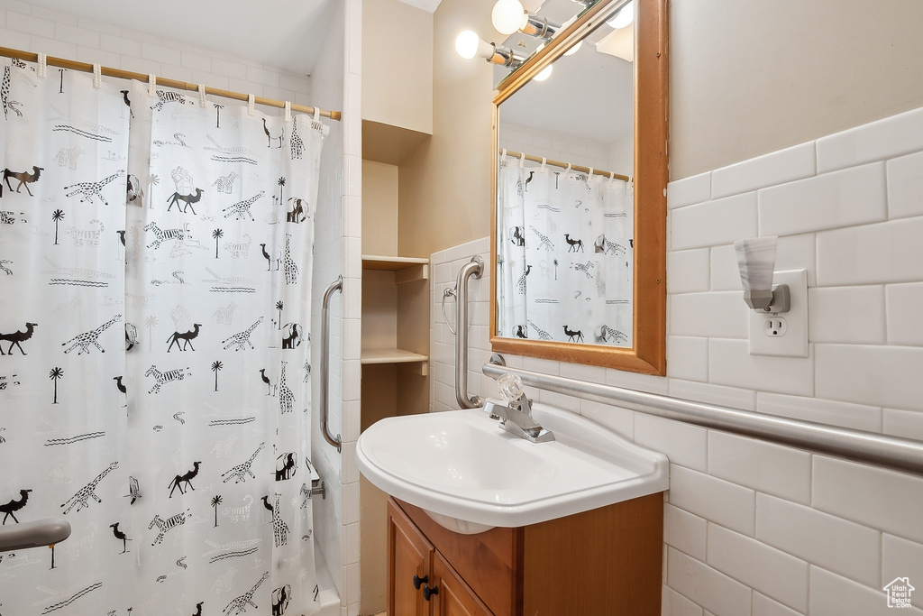Bathroom featuring tile walls, vanity, and curtained shower