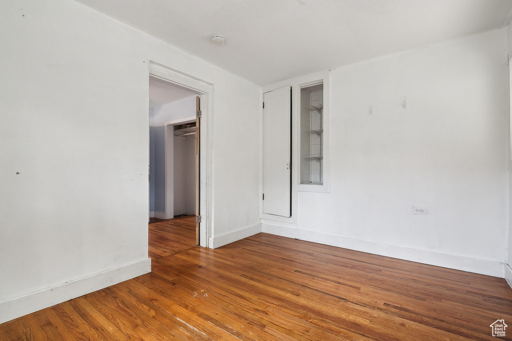 Unfurnished room featuring hardwood / wood-style floors, a smoke detector, and baseboards