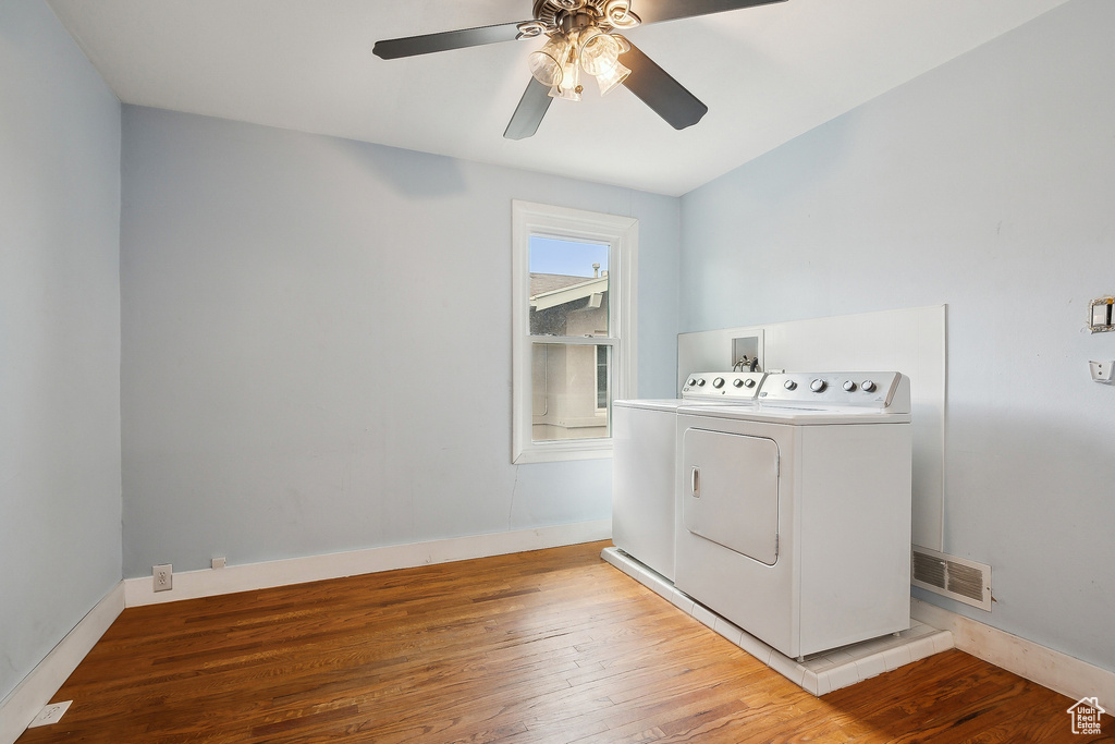 Laundry room featuring washing machine and clothes dryer, light wood-type flooring, a ceiling fan, and baseboards