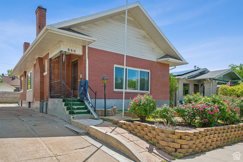 View of front facade featuring a chimney and brick siding