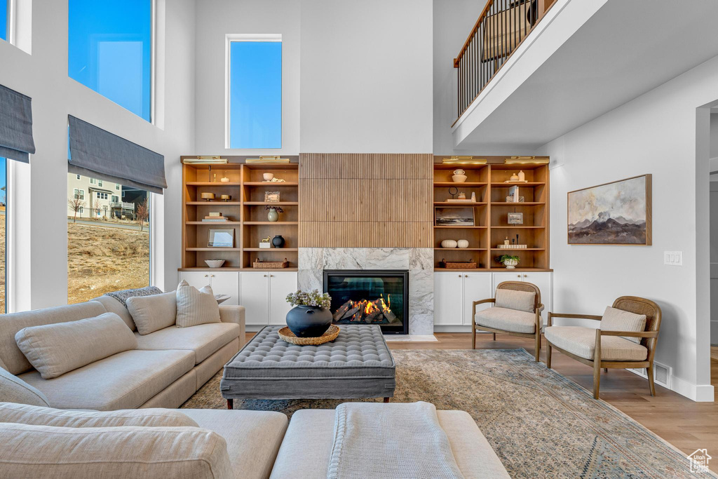 Living room featuring a high ceiling, light wood finished floors, baseboards, and a fireplace