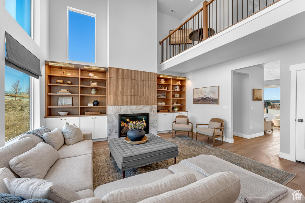 Living area with a towering ceiling, wood finished floors, a high end fireplace, and baseboards