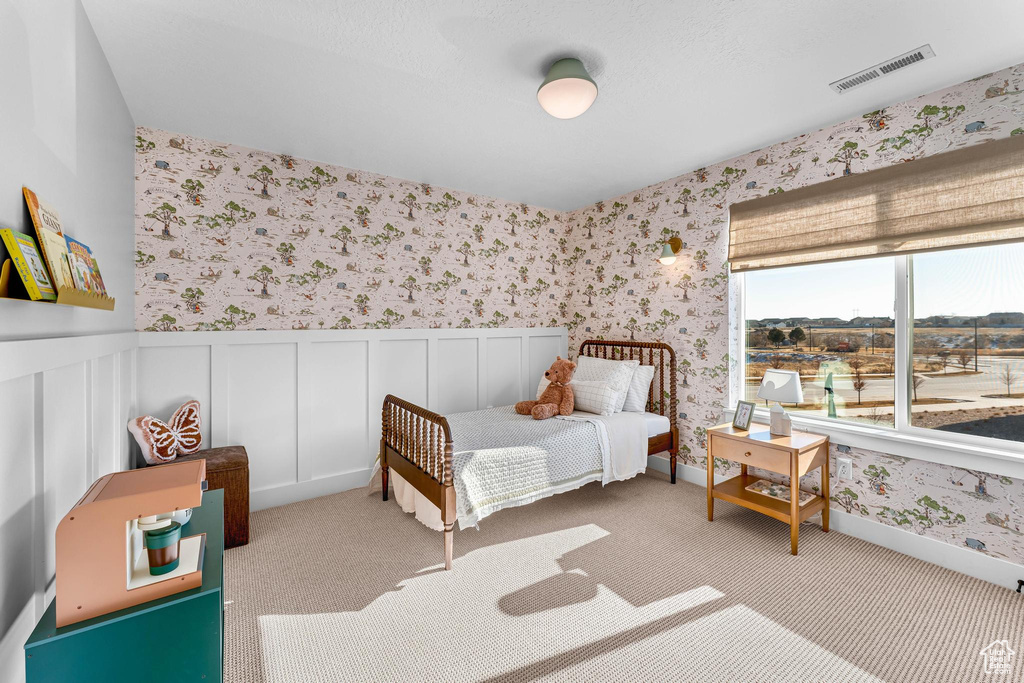 Bedroom featuring wallpapered walls, a wainscoted wall, and carpet
