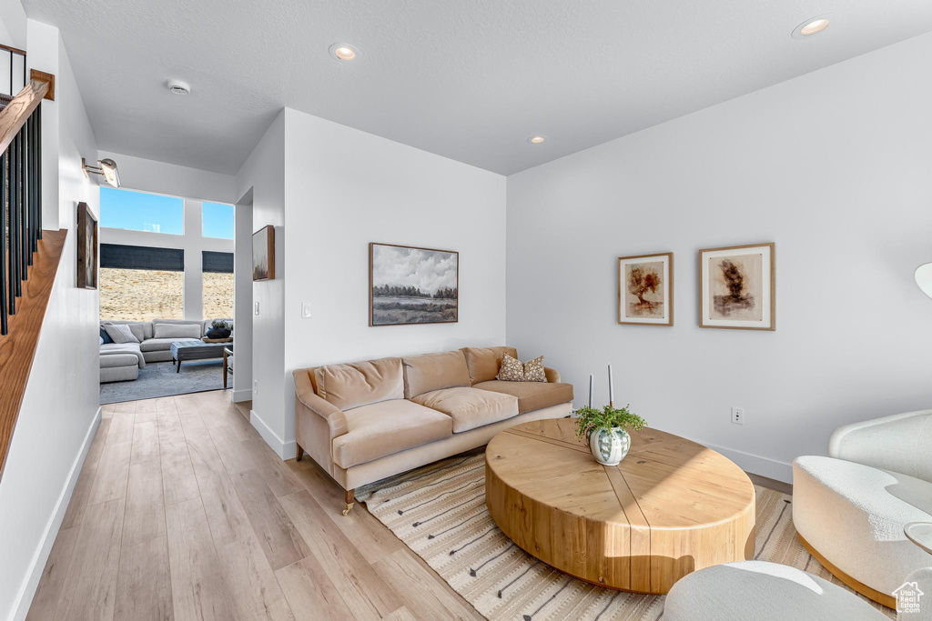 Living area featuring baseboards, light wood-style flooring, recessed lighting, and stairs