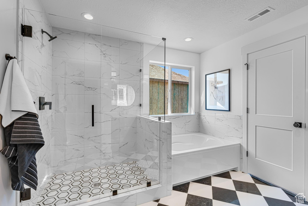 Full bathroom with a marble finish shower, recessed lighting, a bath, tile patterned floors, and a textured ceiling