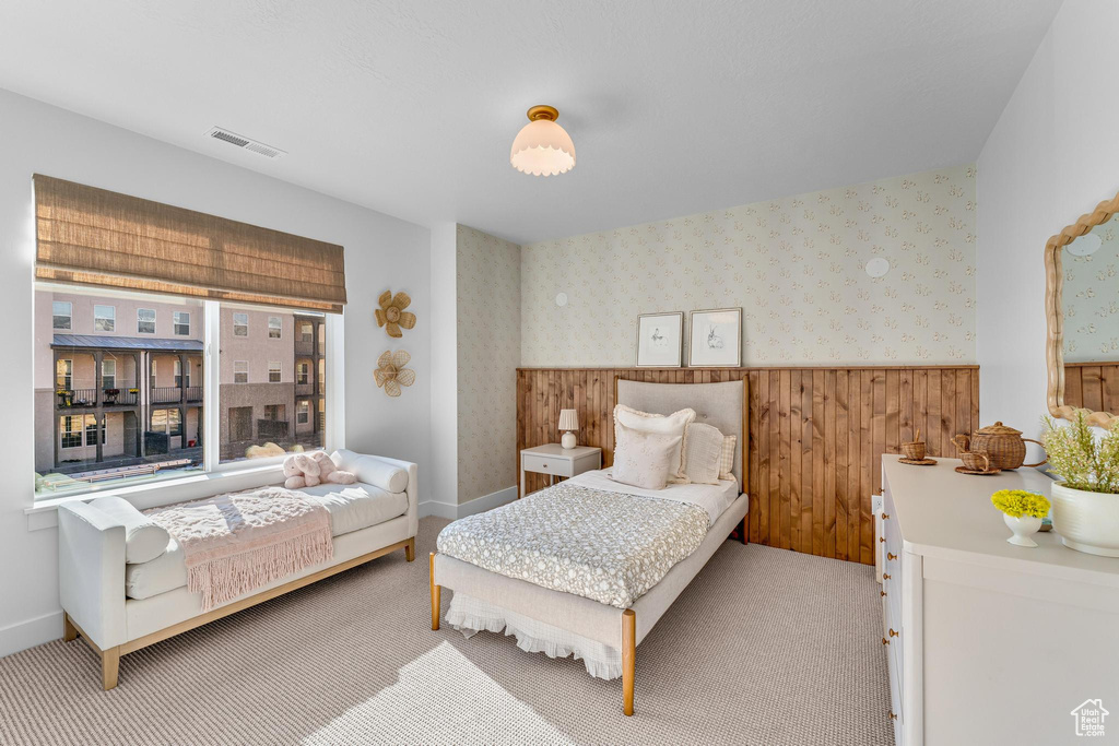 Bedroom featuring a wainscoted wall, wallpapered walls, carpet floors, wood walls, and baseboards