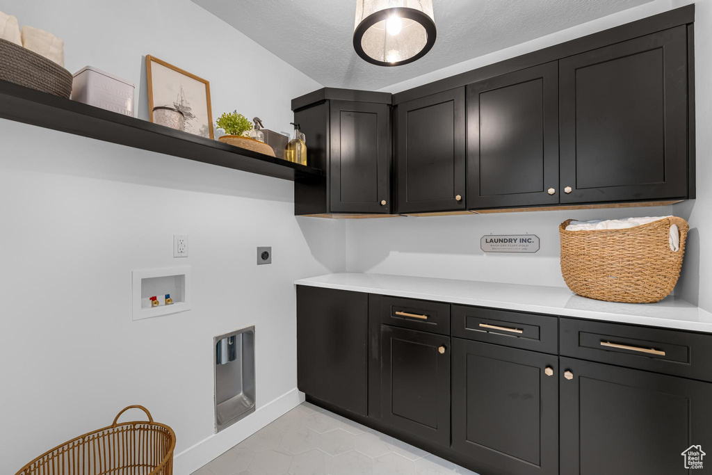 Washroom with cabinet space, hookup for an electric dryer, washer hookup, baseboards, and light tile patterned floors