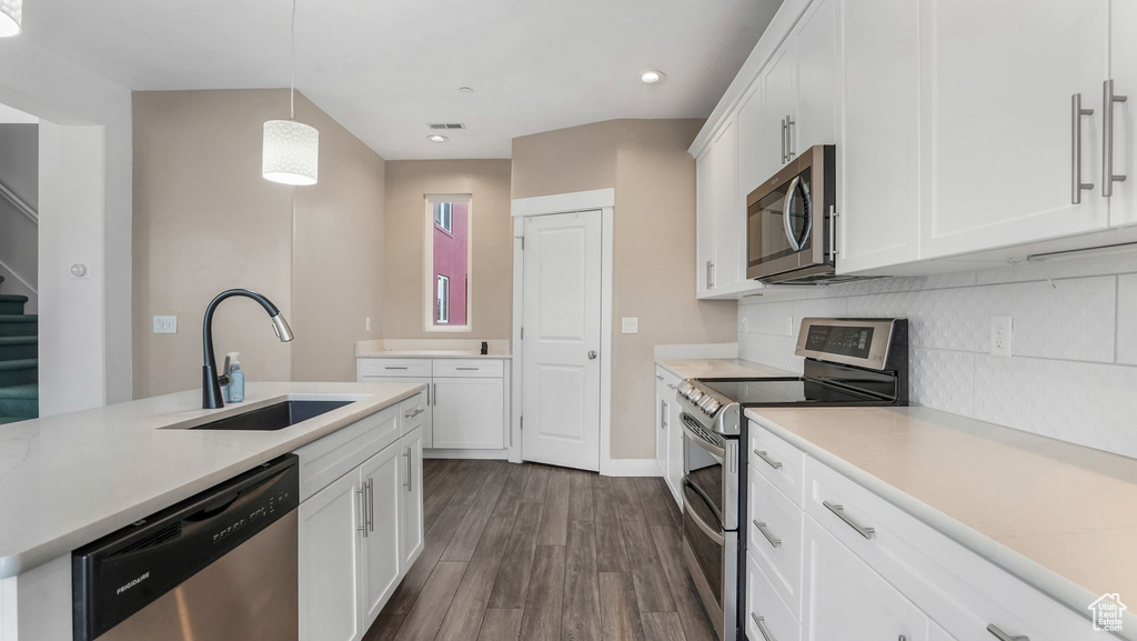 Kitchen featuring appliances with stainless steel finishes, a sink, light countertops, backsplash, and dark wood-type flooring