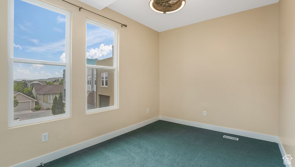 Spare room featuring dark colored carpet and baseboards