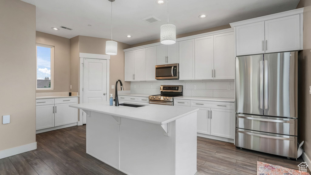 Kitchen featuring stainless steel appliances, a sink, dark wood-type flooring, light countertops, and recessed lighting