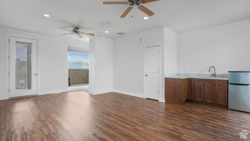 Unfurnished living room with ceiling fan, dark wood-style flooring, a sink, recessed lighting, and baseboards