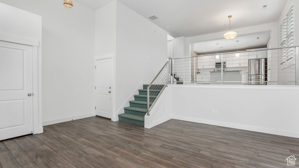 Unfurnished living room with wood finished floors, stairs, and baseboards