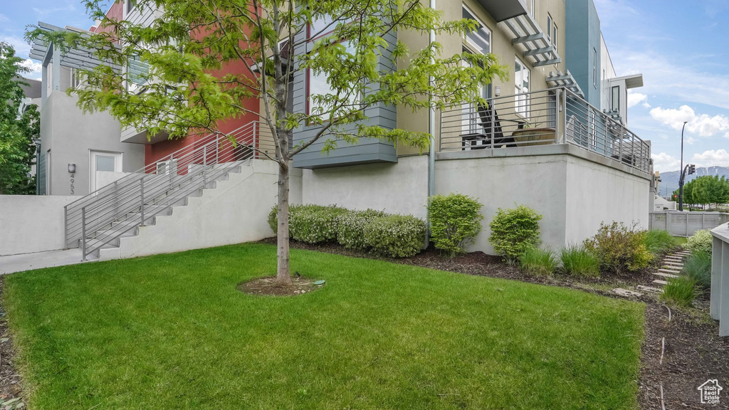 View of side of home with a yard, stucco siding, and stairs