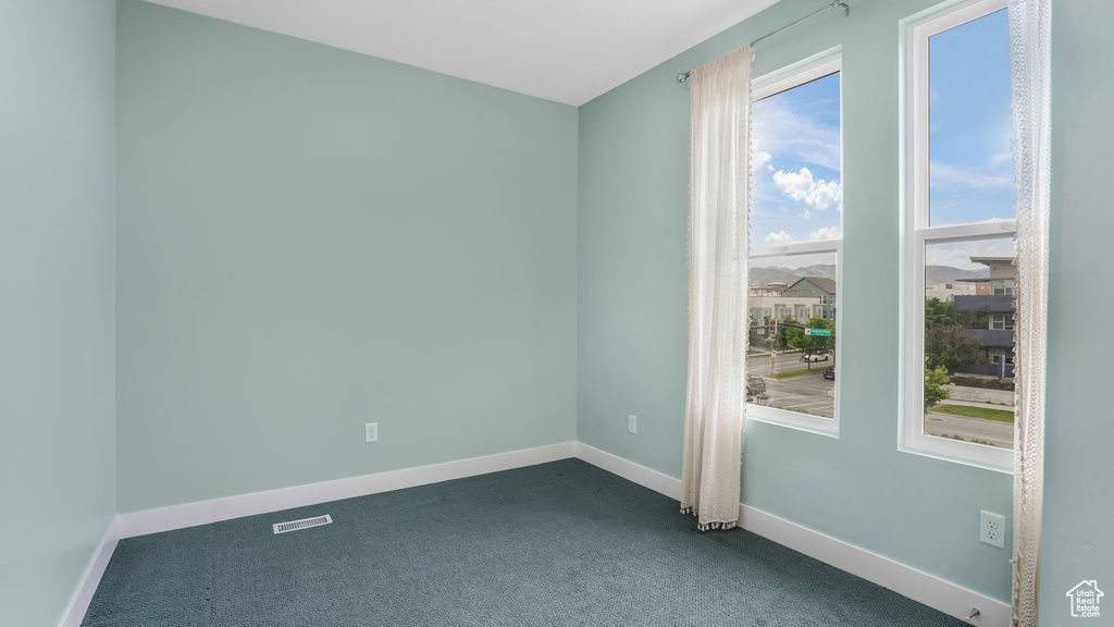 Spare room featuring dark carpet and baseboards