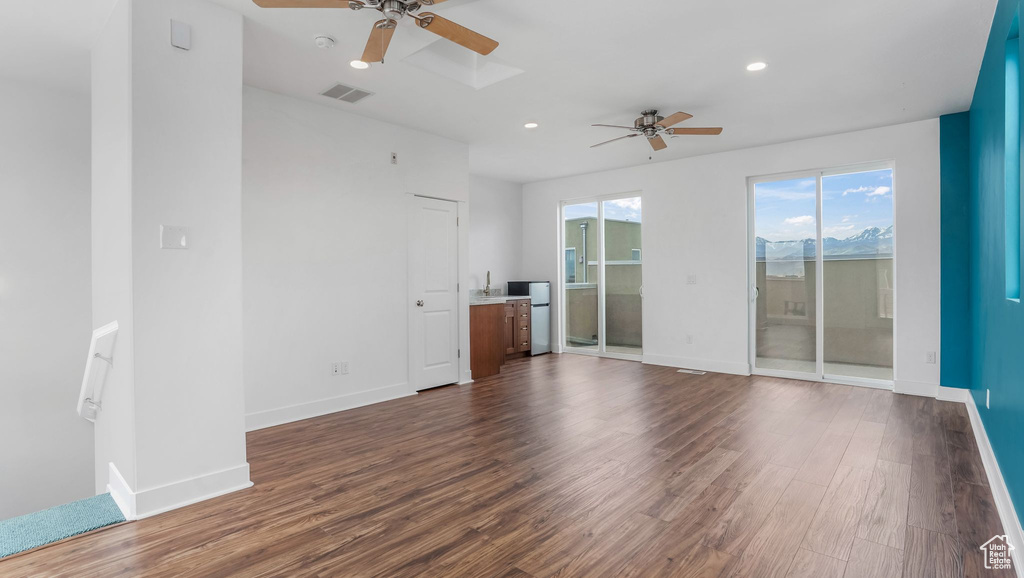 Unfurnished living room featuring a ceiling fan, dark wood-style flooring, baseboards, and recessed lighting