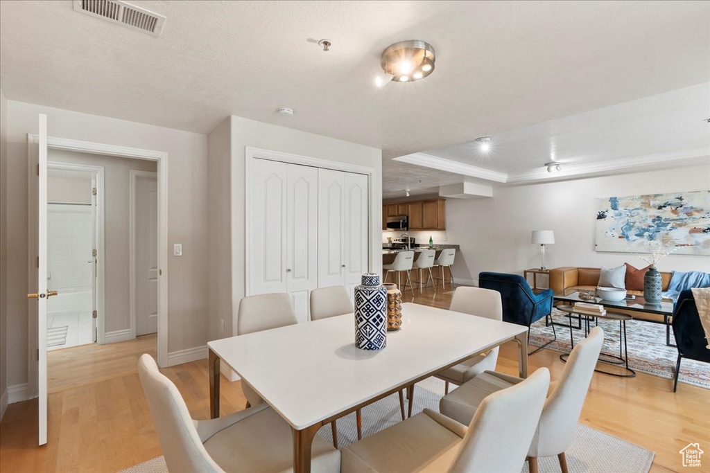 Dining room with light wood-type flooring, baseboards, and a tray ceiling